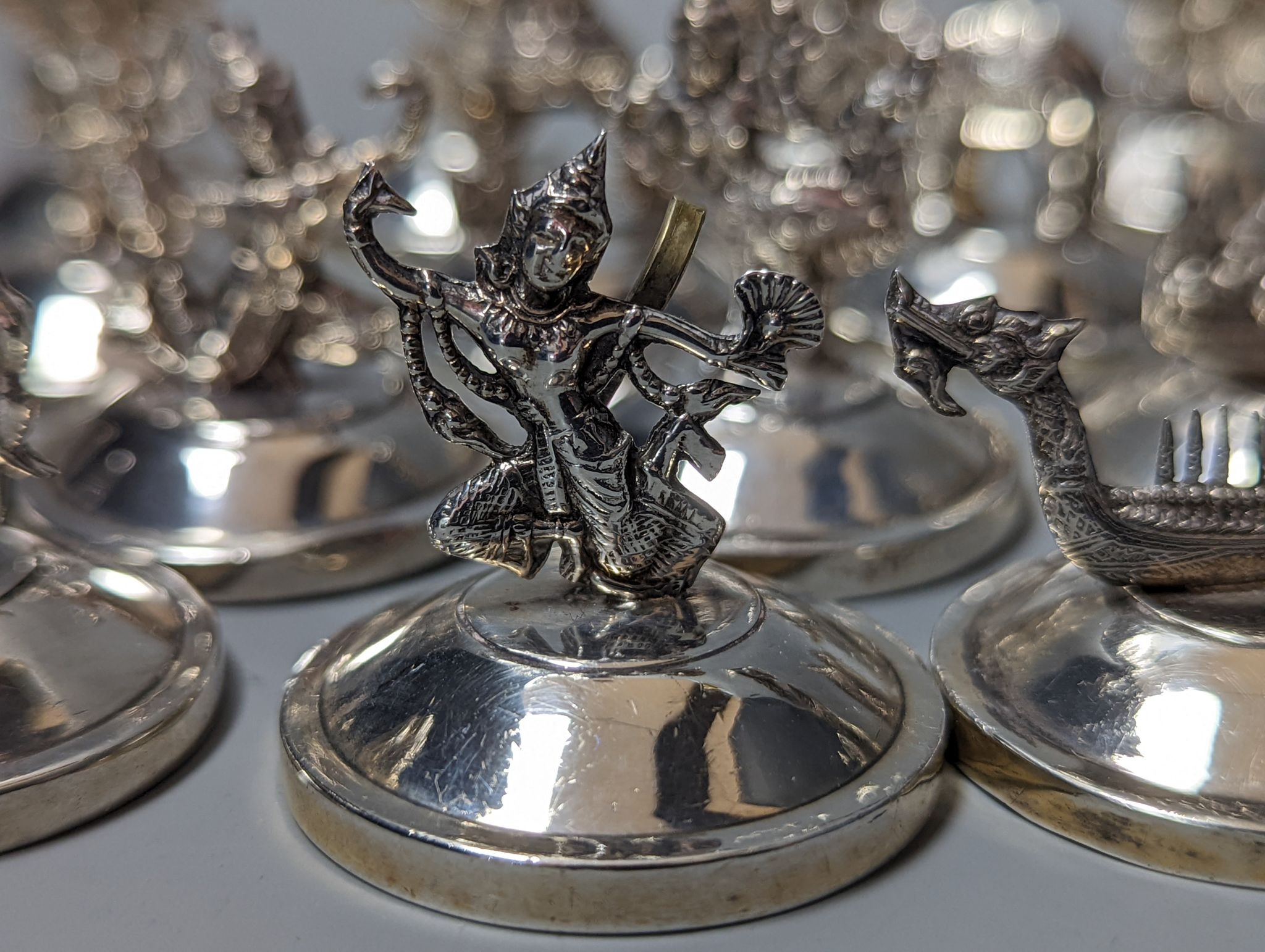 Sixteen assorted Siamese sterling mounted menu holders, modelled with figures, elephant, etc.